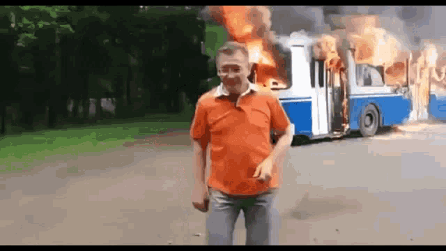 a man standing in front of a burning bus .