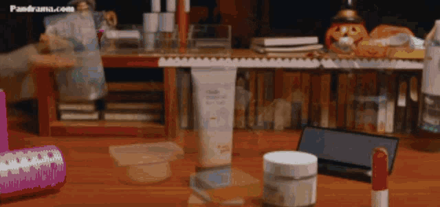 a bottle of lotion sits on a wooden table next to a lipstick