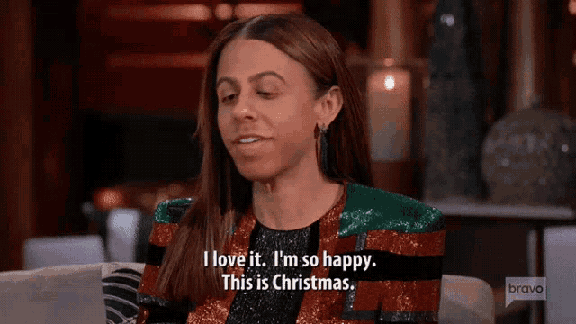 a woman is sitting on a couch and says i love it i 'm so happy this is christmas .