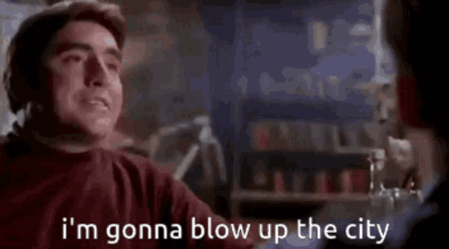 a man is sitting at a table talking to another man and says `` i 'm gonna blow up the city ''