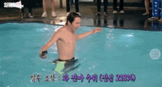 a shirtless man is swimming in a pool with foreign writing on the screen