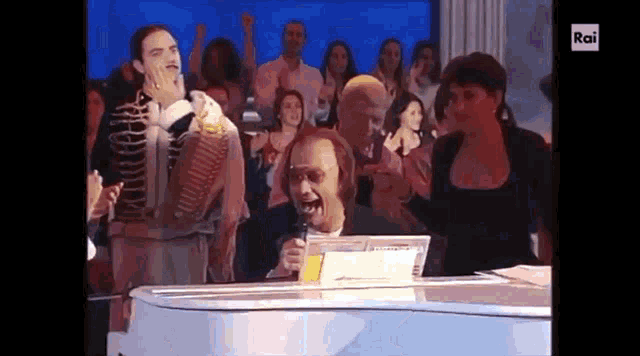 a man is singing into a microphone while standing at a white piano .