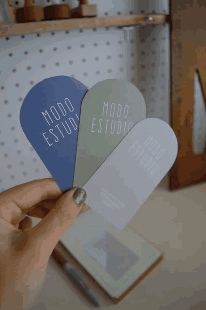 a person is holding three pieces of paper with modo estudio written on them