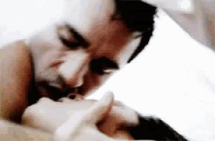a man is kissing a woman on the cheek while laying on a bed .