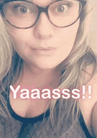 a woman wearing glasses and a black tank top says yaaasss !!