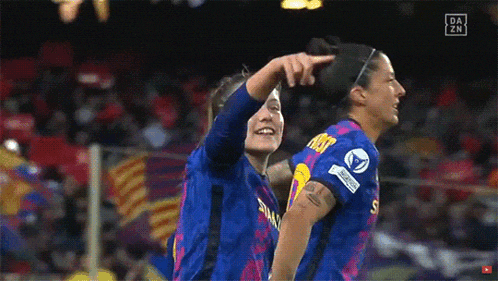 two female soccer players are celebrating a goal and one has the number 5 on her jersey
