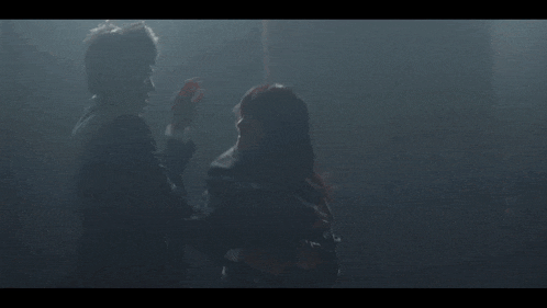 a man is holding another man 's head in a dark room