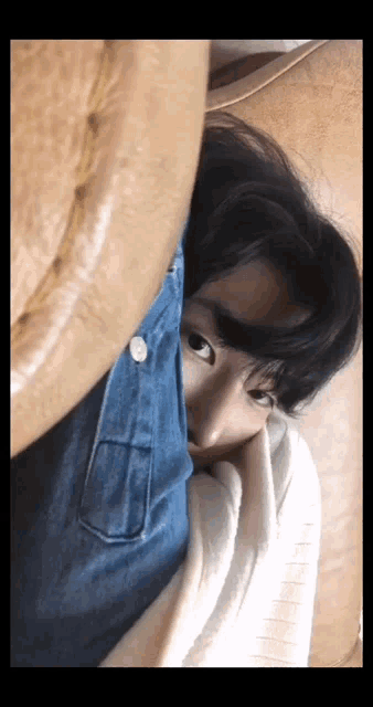 a close up of a person laying on a couch with a blanket