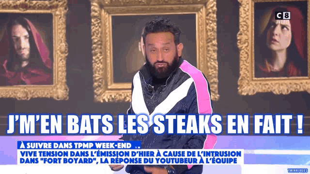 a man in a pink and white jacket stands in front of framed portraits and says i 'm en bats