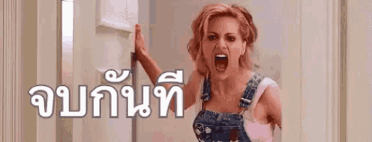 a woman in overalls is screaming and holding a door in a room .