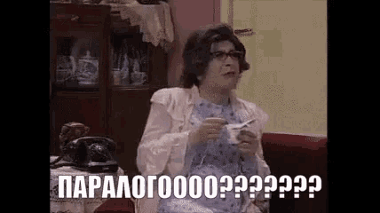 a woman is sitting on a couch holding a cup of coffee and talking on a phone .