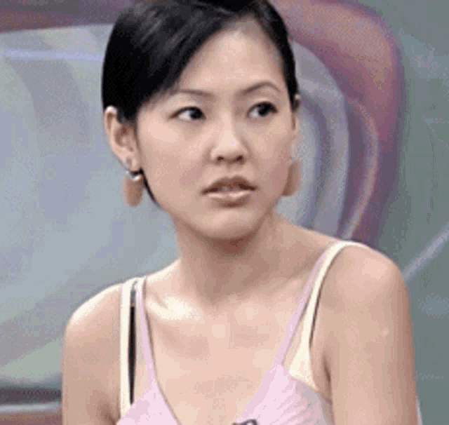 a woman wearing a pink tank top and yellow bra looks at the camera