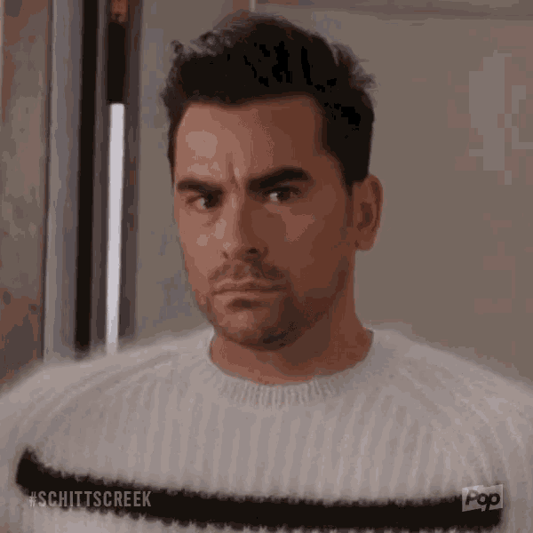 a man with a beard is wearing a fuzzy sweater and looking at the camera .
