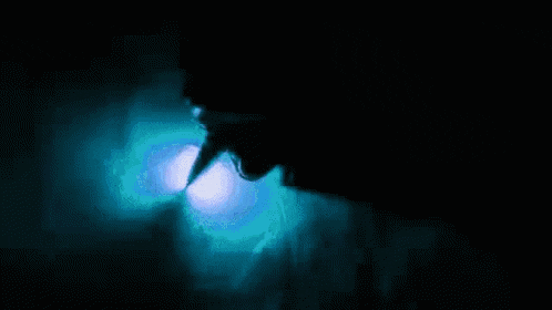 a person is swimming in the dark with a blue light shining on them