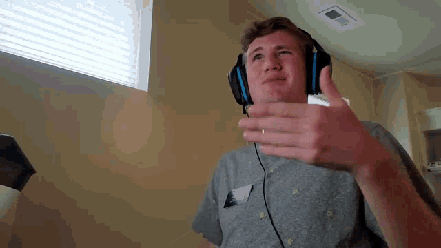 a young man wearing headphones is giving a thumbs up
