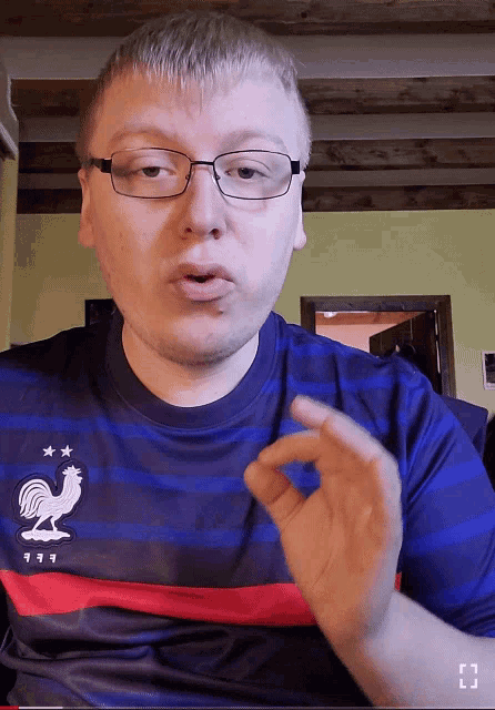 a man wearing glasses and a blue shirt with a rooster on the front