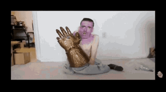 a shirtless man with purple paint on his face is holding a gold glove