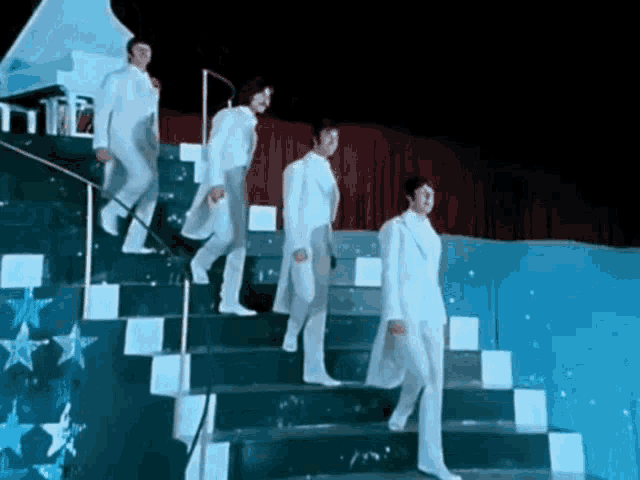 a group of men in white suits are walking up stairs .