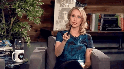 a woman sitting in a chair holding a pipe in front of a poster that says harry pot