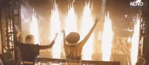 a man and a woman are standing in front of a fireworks display at a party .