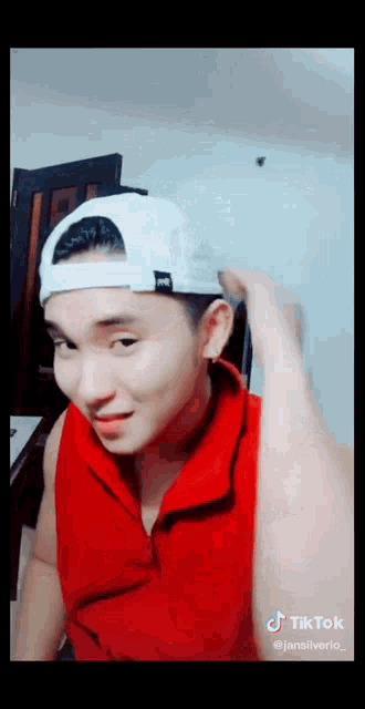 a man wearing a red tank top and a white hat has a tiktok watermark