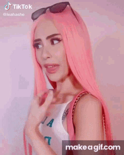 a woman with pink hair is drinking from a pink cup with a straw