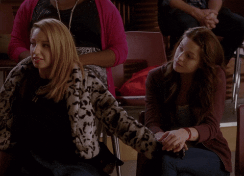 a woman in a leopard print jacket sits next to a woman in a pink cardigan