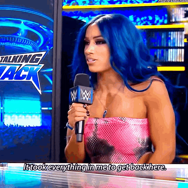 a woman with blue hair is holding a microphone in front of a sign that says talking jack