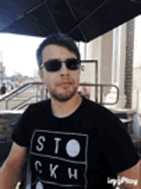 a man wearing sunglasses and a black shirt with the word sto on it .