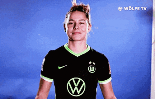 a woman wearing a black and green jersey with a vw logo
