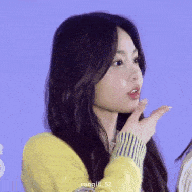 a close up of a woman 's face with a yellow sweater on .