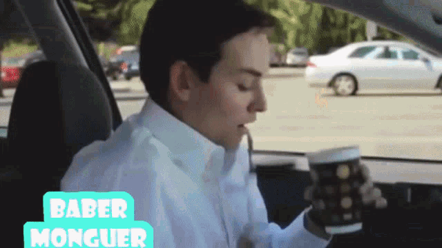 a man is sitting in a car drinking a cup of coffee with the name baber monguer on the bottom