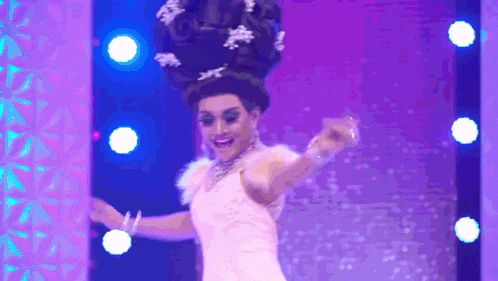 a drag queen is dancing on a stage wearing a large wig .