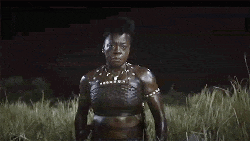 a woman in a crop top is standing in a field of tall grass .