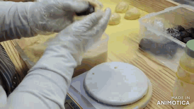 a person wearing gloves is using a scale that says made in animotica