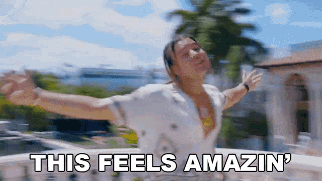 a man is standing on a balcony with his arms outstretched and the words `` this feels amazin '' written below him