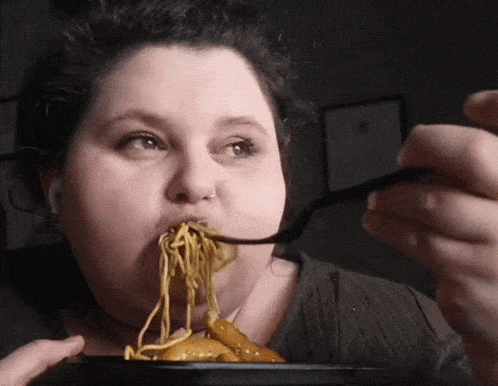 a woman is eating spaghetti with a fork
