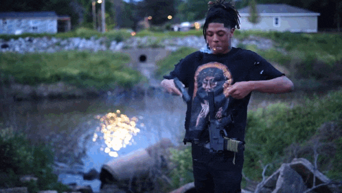 a man wearing a black shirt with a picture of jesus on it is smoking a cigarette