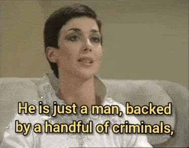 a woman is talking about a man being backed by a handful of criminals