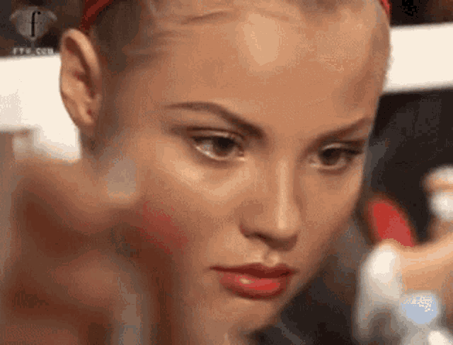 a close up of a woman 's face with the letter f visible in the background