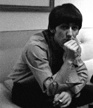 a man is sitting on a couch with his hand on his chin and a cigarette in his mouth .