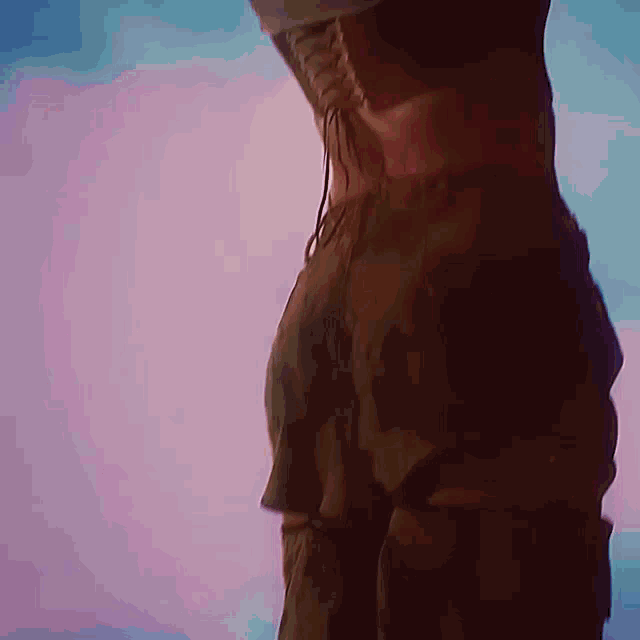 a woman in a lace up top and pants is standing in front of a purple background