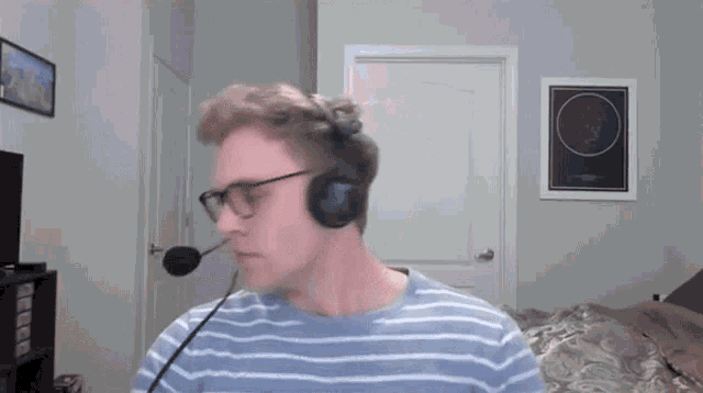 a man wearing headphones and glasses stands in front of a door