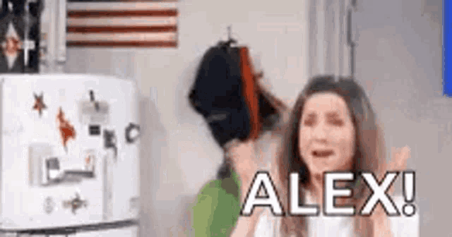 a woman is crying in front of a refrigerator and the word alex is on the refrigerator door .