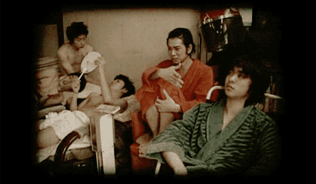 a group of people are gathered in a room and one of them is wearing a green striped robe