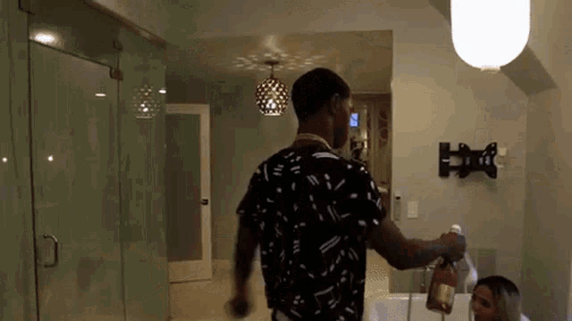 a man is pouring champagne into a bottle in a bathroom .