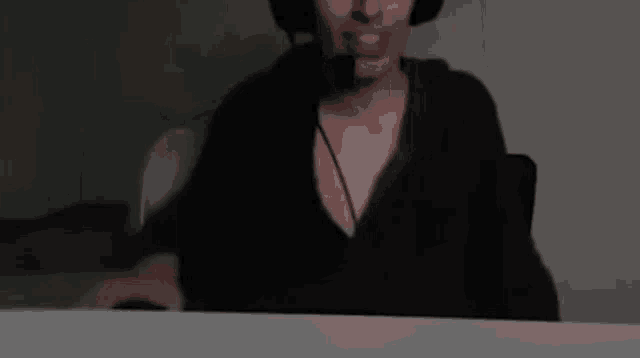 a woman wearing headphones and a microphone is sitting at a desk .