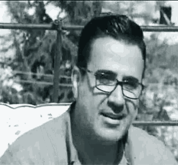 a black and white photo of a man wearing glasses and a jacket .