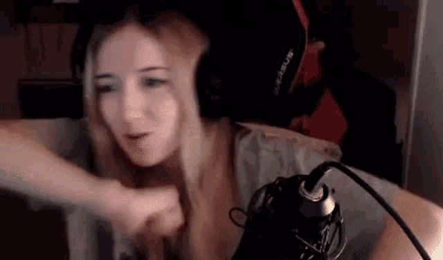 a woman wearing headphones is sitting in front of a microphone and making a funny face .