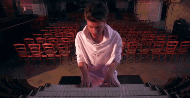 a man in a white hoodie is playing a piano in a church